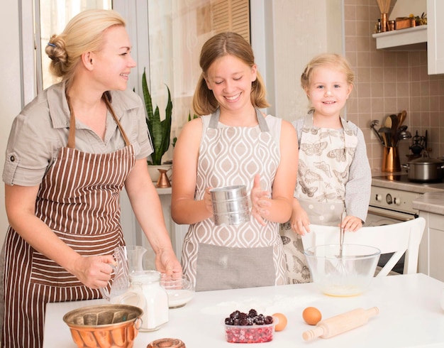 Família feliz na cozinha Mãe e filhas se divertindo assando em casa Conceito de comida doméstica