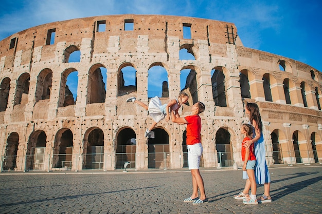 Família feliz na europa pais e filhos em roma sobre o fundo do coliseu