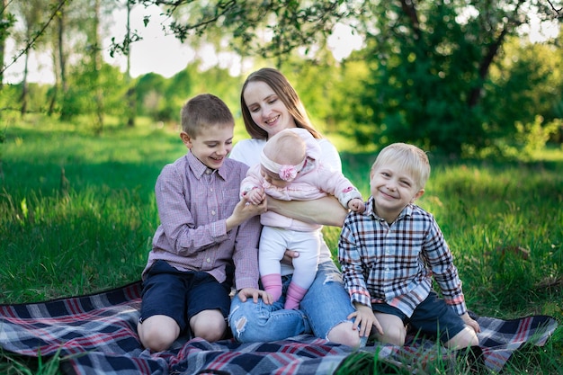 Família feliz na natureza piquenique de verão em família no parque jovem mãe e três filhos