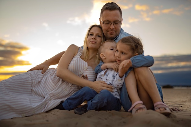 Família feliz na praia sentada na areia ao pôr do sol