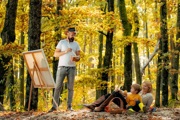 Família feliz nas férias de outono. Pai pintor à procura de sua esposa e filho. conceito.