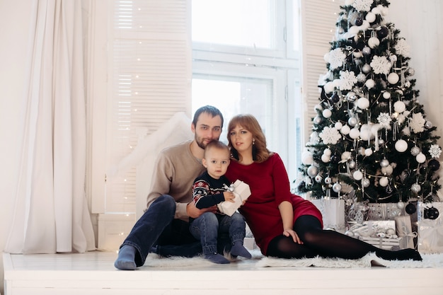 Familia feliz bajo la nieve por el árbol.