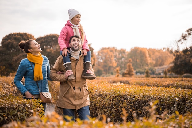 Familia feliz con un niño caminando en el hermoso parque de otoño