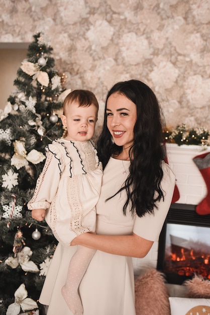 Familia feliz con el niño celebrando el año nuevo y la Navidad en el árbol de Navidad decorado y guirnaldas