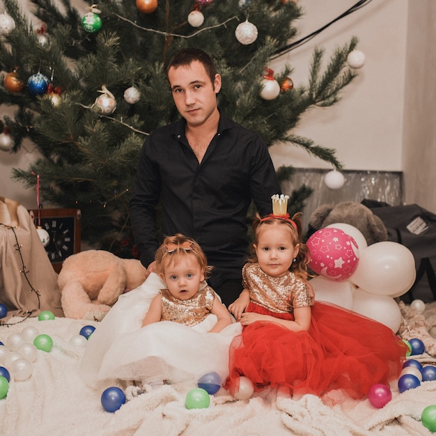Familia feliz con el niño celebrando el año nuevo y la Navidad en el árbol de Navidad decorado y guirnaldas