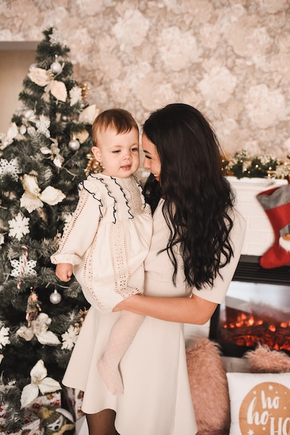 Familia feliz con el niño celebrando el año nuevo y la Navidad en el árbol de Navidad decorado y guirnaldas