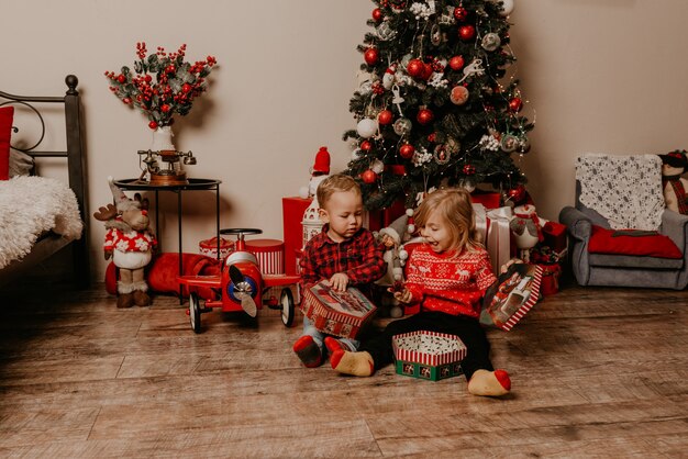 Familia feliz con el niño celebrando el año nuevo y la Navidad en el árbol de Navidad decorado y guirnaldas