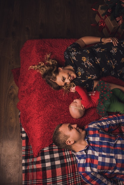 Familia feliz con el niño celebrando el año nuevo y la Navidad en el árbol de Navidad decorado y guirnaldas