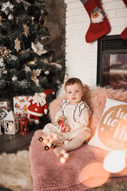 Familia feliz con el niño celebrando el año nuevo y la Navidad en el árbol de Navidad decorado y guirnaldas