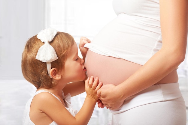 Familia feliz Niño feliz besando el vientre de la madre embarazada