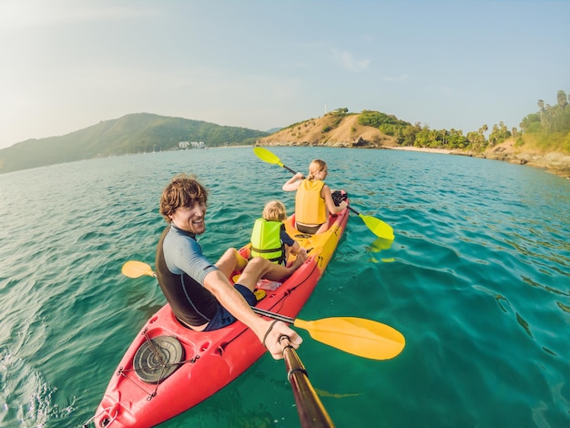 Familia feliz con niño en kayak en el océano tropical