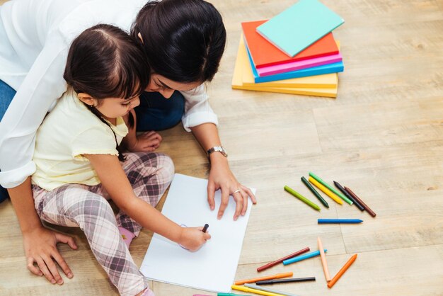 Familia feliz niño niño niña jardín de infantes dibujo maestro educación madre mamá con hermosa madre en el interior de la casa