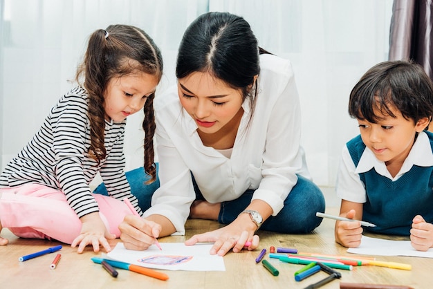 Familia feliz niño niño niña jardín de infantes pintura dibujo sobre la educación de maestros de peper con madre mamá en la sala de juegos interior