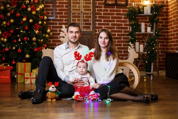 Una familia feliz con un niño pequeño se encuentra cerca de un árbol de Navidad con juguetes y regalos. Infancia feliz. Ambiente festivo de año nuevo. Concepto de relación familiar