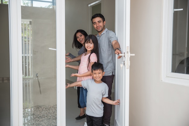 Familia feliz con niños abre la puerta de su casa