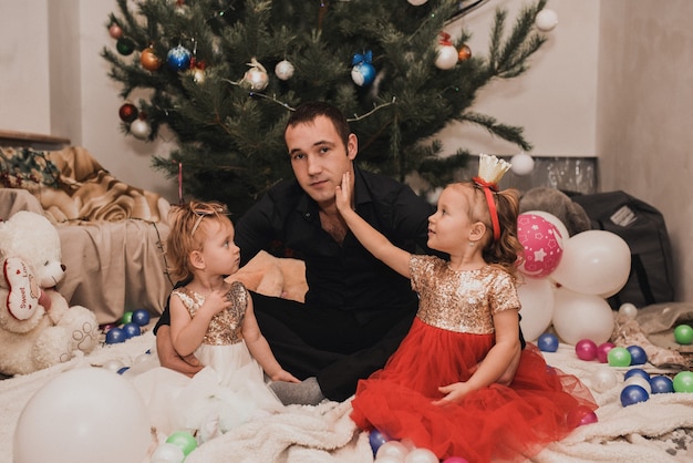 Familia feliz con niños celebrando el año nuevo y la Navidad en guirnaldas de árboles de Navidad decorados