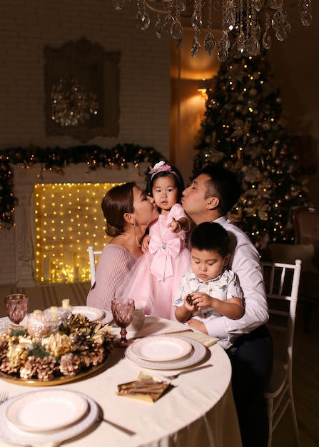 Foto familia feliz con niños celebrando la cena de navidad junto al árbol por la noche