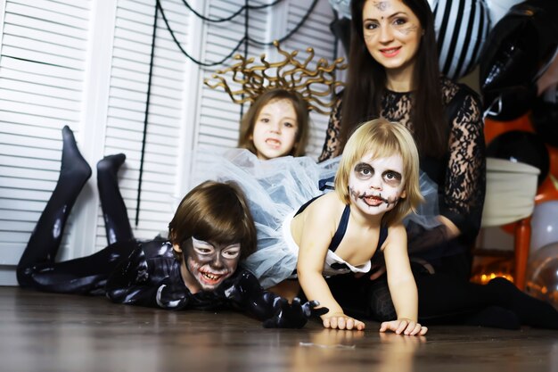 Familia feliz con niños en disfraces y maquillaje en celebración de Halloween