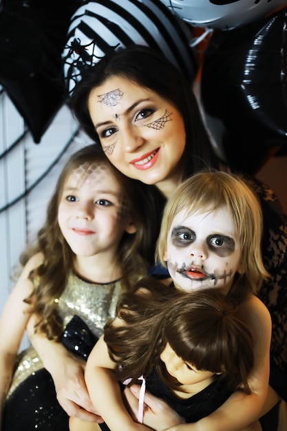 Familia feliz con niños en disfraces y maquillaje en celebración de Halloween