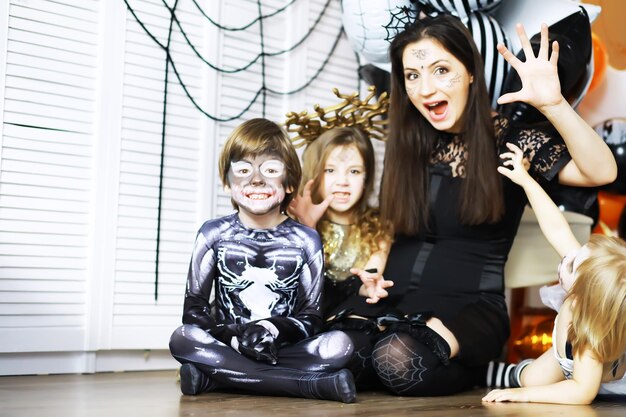 Familia feliz con niños en disfraces y maquillaje en celebración de Halloween