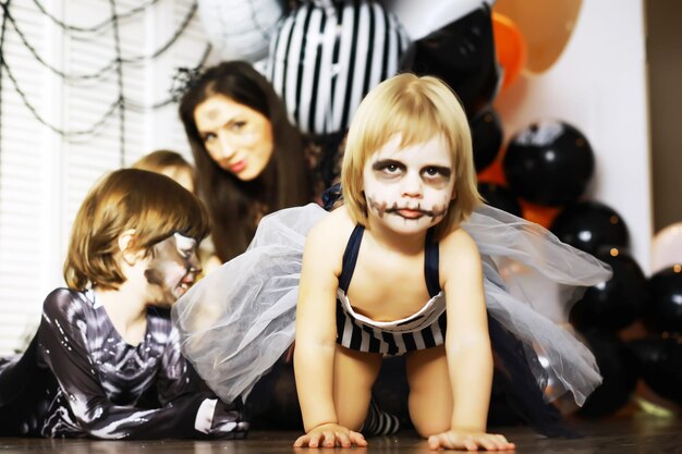 Familia feliz con niños en disfraces y maquillaje en celebración de Halloween