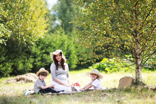 Familia feliz con niños haciendo un picnic en el parque, padres con niños sentados en el césped del jardín y comiendo sandía al aire libre