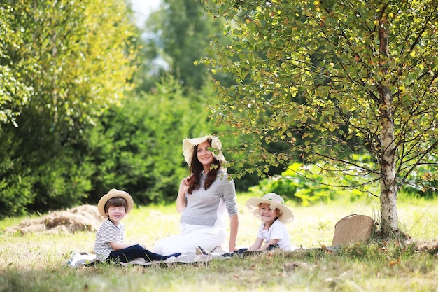 Familia feliz con niños haciendo un picnic en el parque, padres con niños sentados en el césped del jardín y comiendo sandía al aire libre