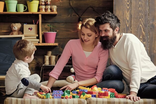 Familia feliz niños jugando con juguetes padre madre e hijo lindo jugar con ladrillos constructor concepto de padres cariñosos