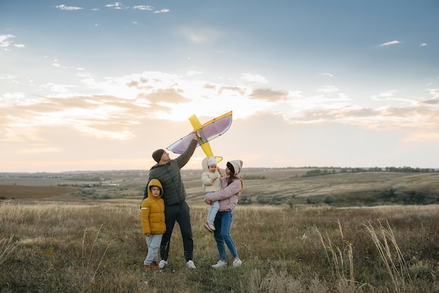 Una familia feliz con niños lanza una cometa y pasa tiempo juntos al aire libre. Felices vacaciones en familia e infancia.