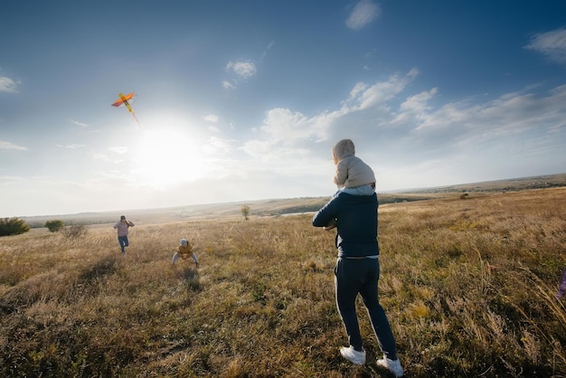 Una familia feliz con niños lanza una cometa y pasa tiempo juntos al aire libre. Felices vacaciones en familia e infancia.