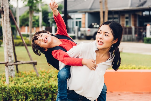 Familia feliz niños niño hijo niño kindergarten jugando paseo piggyback madre mamá en el parque al aire libre