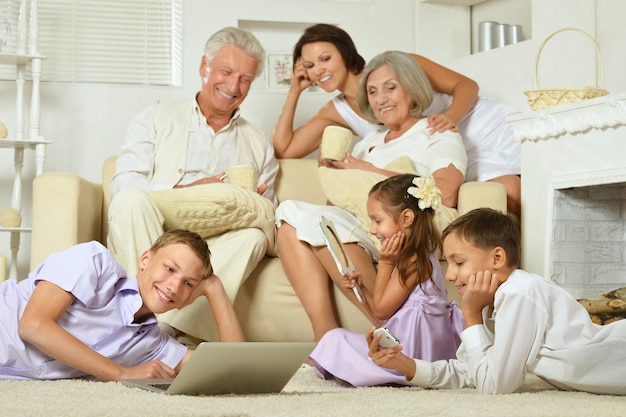 Familia feliz con niños y portátil en el sofá en la sala de estar