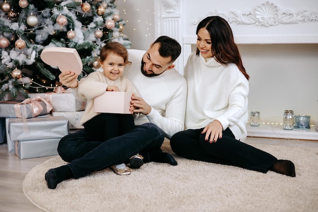 Familia feliz con niños y regalos de Navidad en el suelo en casa