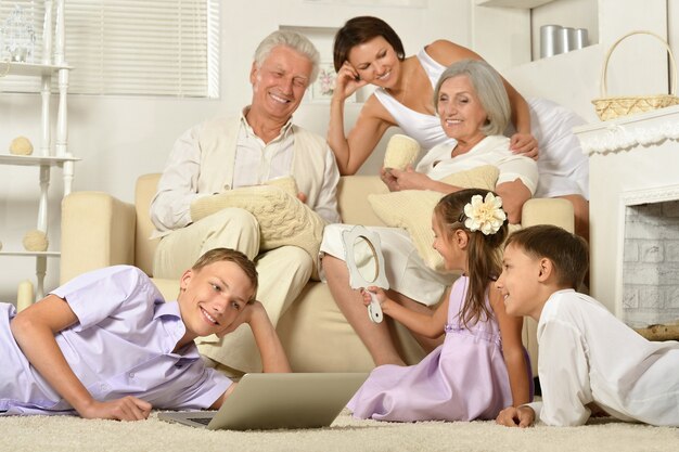 Familia feliz con niños en el sofá en la sala de estar con un portátil