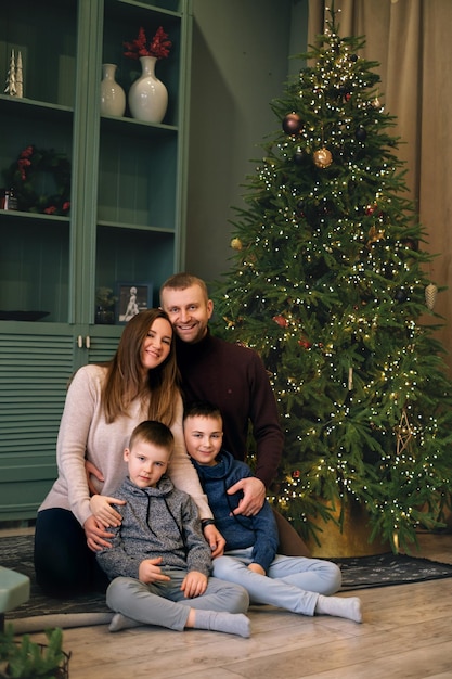 Familia feliz con niños toman fotos conjuntas en el árbol de Navidad