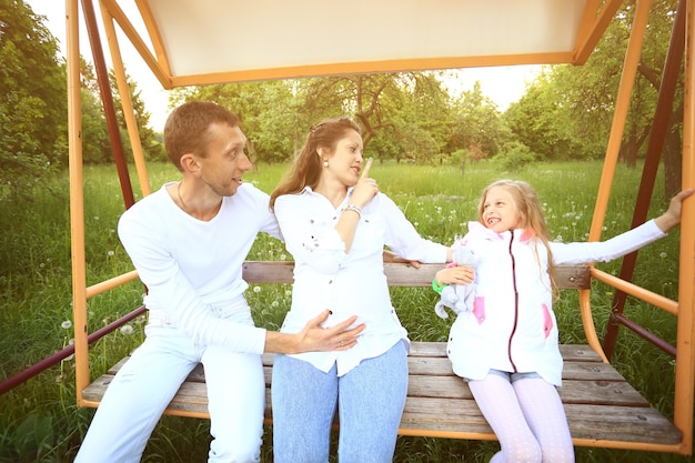 Família feliz no balanço do jardim no domingo