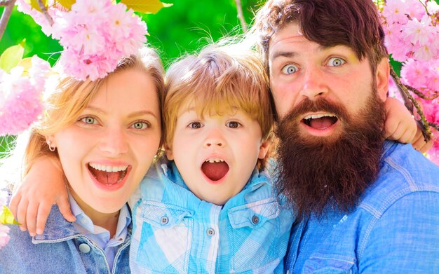 Família feliz no jardim primavera. pai mãe com filho pequeno juntos em flor de sakura. casal feliz no parque sakura.