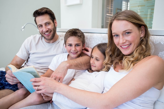 Família feliz no livro de leitura da cama