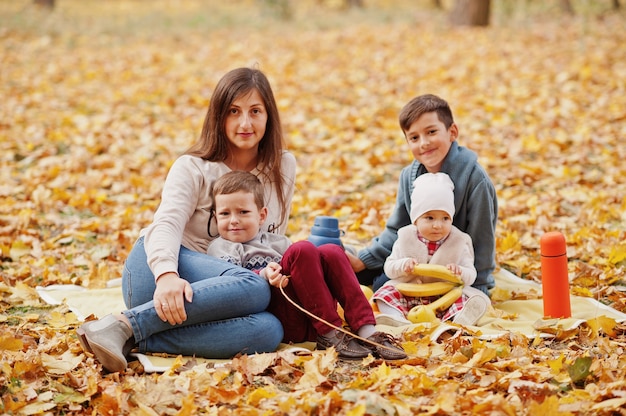 Família feliz no parque de folhas de outono. Mãe com três filhos.