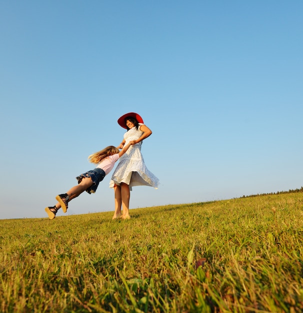 Família feliz no prado de verão bonito tendo tempo feliz circlin ao redor