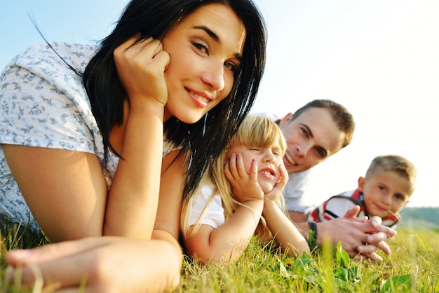 Família feliz no prado de verão bonito tendo tempo feliz