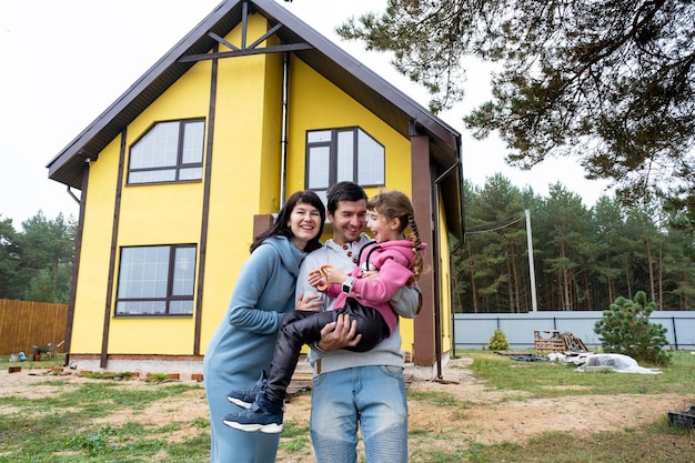 Família feliz no quintal de uma casa inacabada compra de uma construção de realocação de empréstimo hipotecário cottage