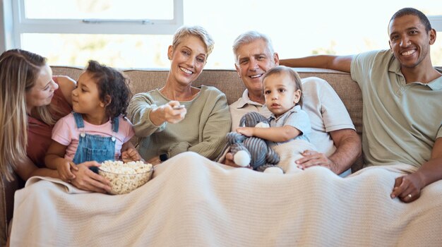 Família feliz no sofá assistindo tv com pipoca e crianças mostram filme ou filme de comédia no serviço de transmissão ao vivo Televisão relaxa e avós com crianças no sofá com diversidade de amor e conversando