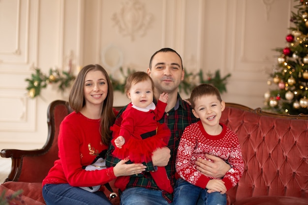 Família feliz no sofá perto da árvore de natal. atmosfera familiar acolhedora. desfrutando de abraços de amor, pessoas de férias. conceito de união.