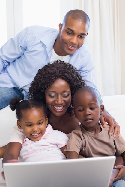 Família feliz no sofá usando o laptop