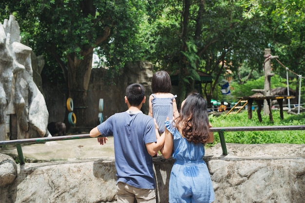 Família feliz no zoológico olhando um urso