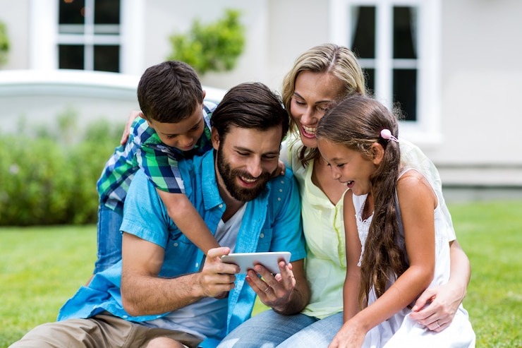 Foto família feliz, olhando para o telefone móvel no quintal