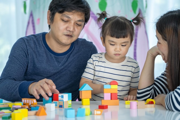 Família feliz Os pais brincam de brinquedos de desenvolvimento com sua filhinha em um lar doce lar