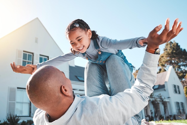 Família feliz ou pai levanta menina no jardim de casa para passar um tempo de qualidade ou brincar ao ar livre ame a nova casa e o pai com a criança voando no ar e sorria no fim de semana das férias de verão e no jogo de férias