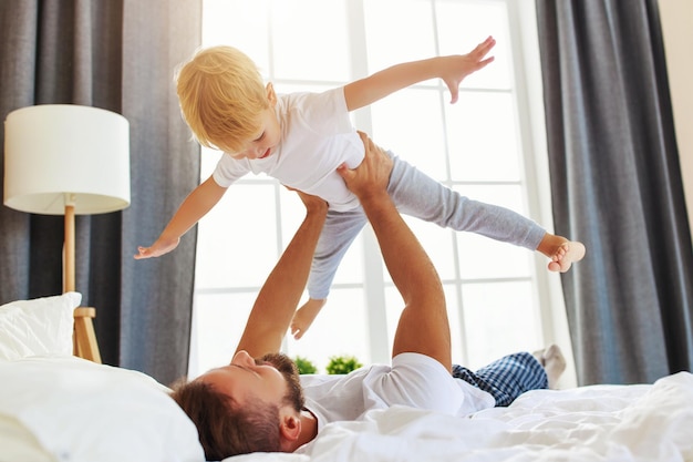 Familia feliz padre e hijo hijo en casa en la cama